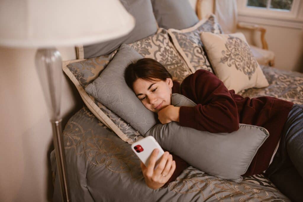 woman using her phone while in bed